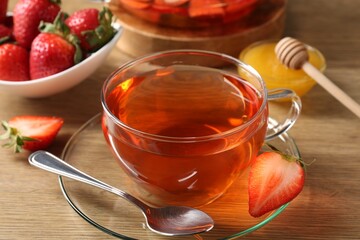 Aromatic fruit tea with strawberries and honey on wooden table, closeup