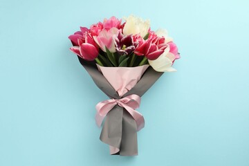 Bouquet of beautiful tulips on light blue background, top view