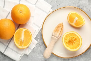 Wooden juicer and fresh oranges on grey table, flat lay