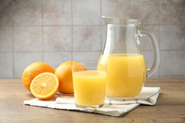 Fresh orange juice and fruits on wooden table against grey tiled wall, closeup
