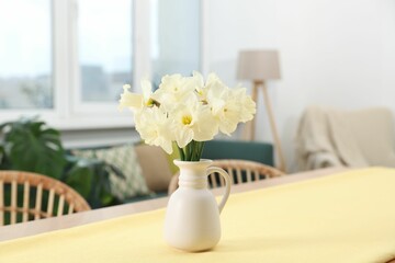 Beautiful daffodils in vase on table at home