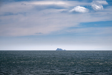 Obraz premium an island visible on the horizon in the open sea.