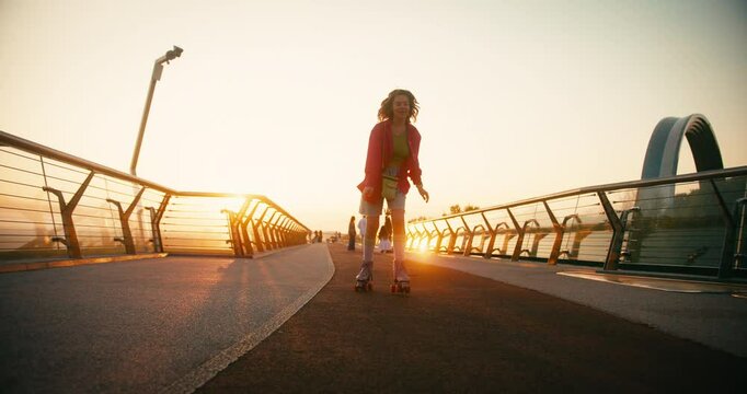 Multicultural Women in Casual Clothes Riding Roller Skates. Fit Beautiful Friends Moving and Spinning Around while Entertaining during Sunrise. Fitness Youth Culture Diversity