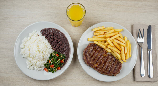 Comida t&iacute;pica de almo&ccedil;o brasileiro - arroz feij&atilde;o, couve bisteca de carne e batata frita com com suco