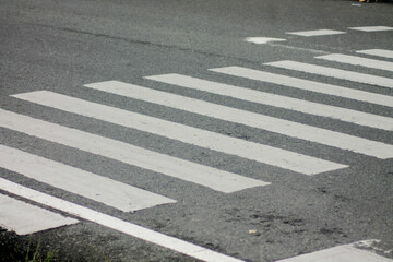 Zebra crosswalk on a asphalt road - closeup background	
