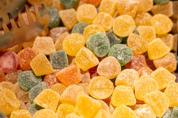 Colorful gummy candies displayed in a market during a sunny day, inviting visitors to indulge in...