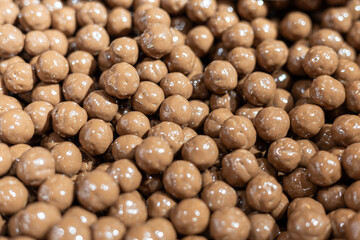Chocolate-coated snack balls displayed in a vibrant market during a sunny afternoon in a bustling city