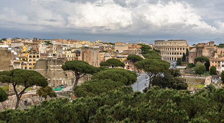 Fototapeta premium Historic landscape featuring ancient ruins and the Colosseum in Rome with overcast skies during midday