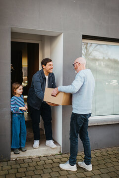 delivery man handing over package to happy family at door
