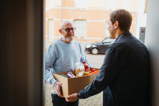 man receives a box of groceries at his doorstep.