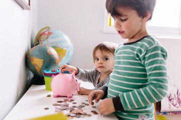 Kids put money in piggy bank