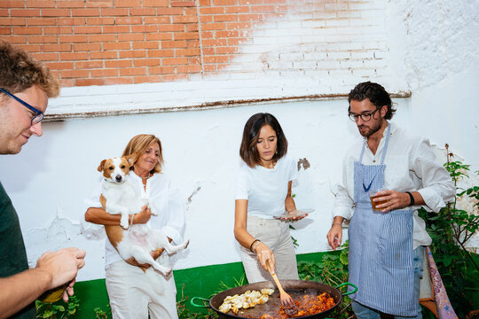 Happy family cooking shrimps on paella pan with dog