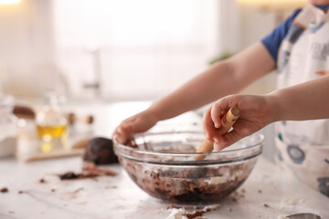 Cooking recipe. Little boy making dough for cookies at table in kitchen, closeup. Space for text