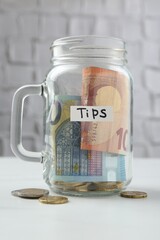 Tips jar with money on white table