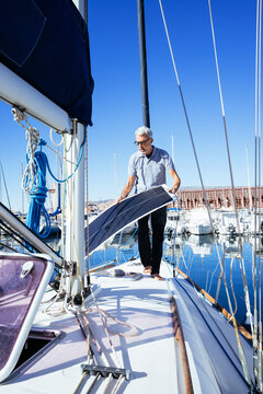 Mature man standing with solar panel on sailboat