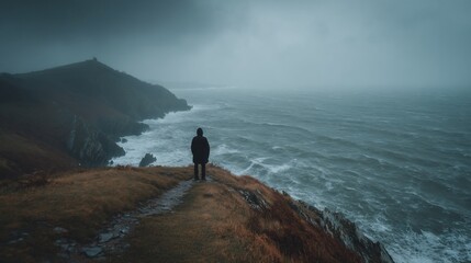 Person on cliff overlooking stormy sea
