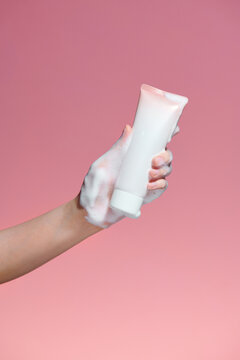 Woman hand-holding cosmetic bottle with foam bubbles
