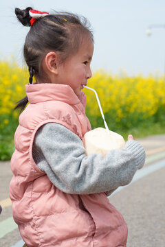 side view of lovely asian kid dringking coconut at spring field