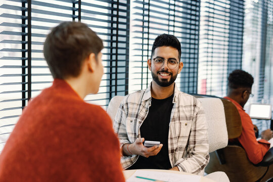 Smiling digital company male employee working with female colleague