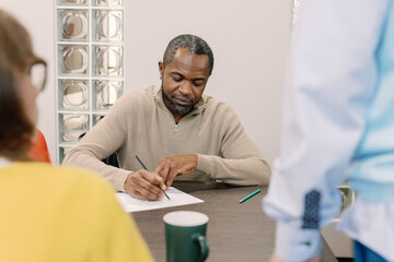 IT company employee writing on paper during meeting with coworkers