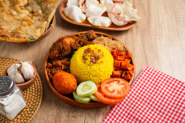 Nasi Kuning. Yellow rice is a typical Indonesian food. This food is made from rice cooked with turmeric, coconut milk, spices and served with fried chicken, egg balado, sambal, and crackers. 