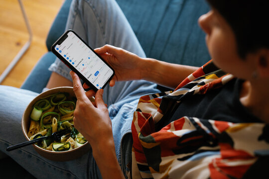 Businesswoman watching graphs in app on smartphone and eating salad
