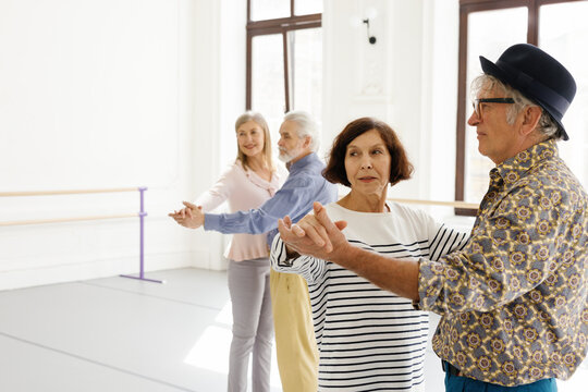 Pairs of elderly people standing in dance pose at dance school