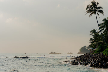Remote view of woman looking at the ocean on tropical beach 
