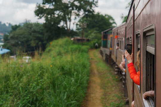 Woman photographing with smartphone from train on Sri Lanka 
