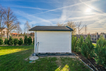 Wooden painted in white shed in the garden under clear blue sky