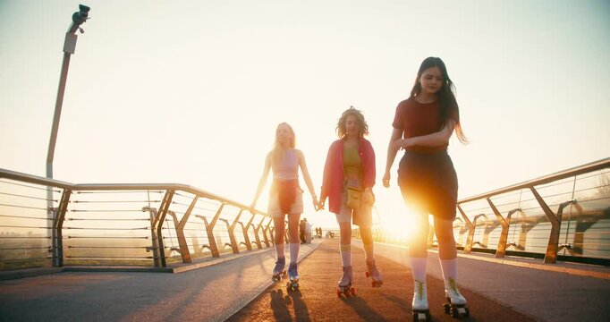 Multicultural Women in Casual Clothes Riding Roller Skates. Fit Beautiful Friends Moving and Spinning Around while Entertaining during Sunrise. Fitness Youth Culture Diversity