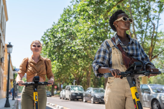 Excited tourists exploring summer city on e-scooters