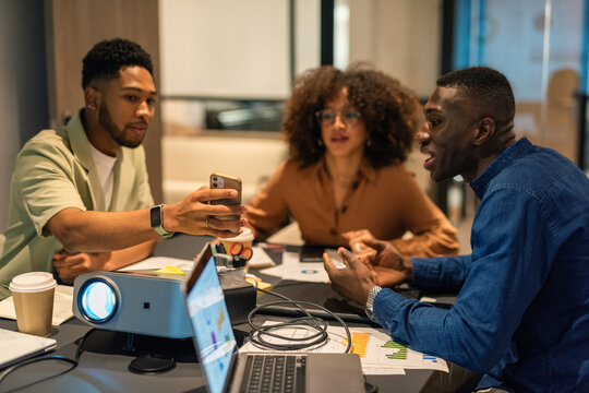 Man showing information on smartphone to colleagues