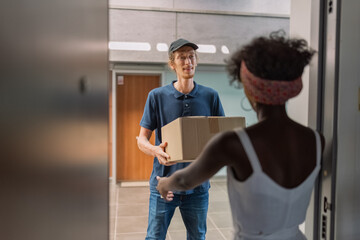 Smiling postman giving box to happy customer