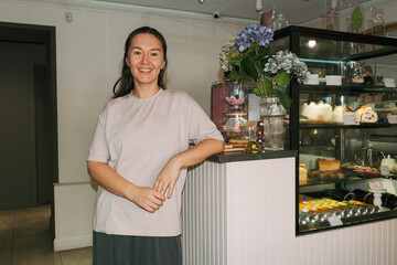 Cafe owner stands proudly by the display case in her coffee shop