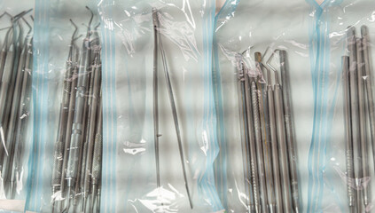 Sets of dental instruments sealed in sterile packaging after autoclaving. Focus on hygiene, infection control, and preparation for dental procedures