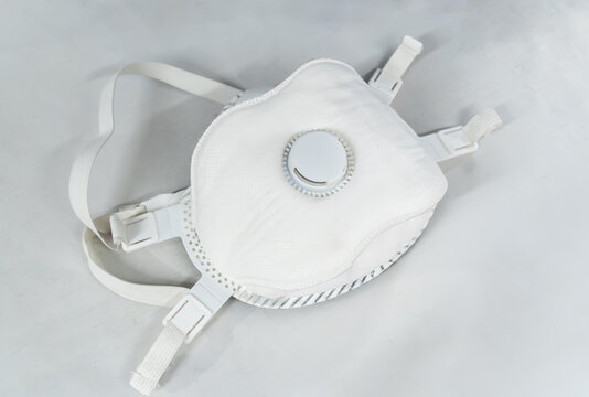A white KN95 face mask with adjustable ear straps isolated on a pristine white surface