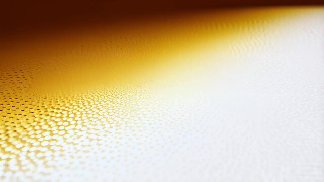 Golden pointillist texture fades into soft gradient of amber and cream, glowing gently with intricate dot patterns across the surface. Concept of abstract detail and artistic light expression