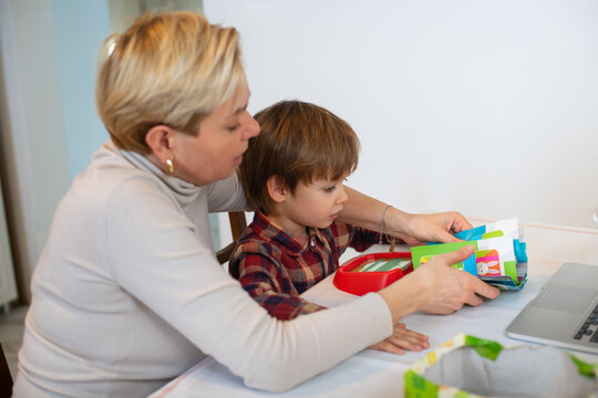 Autistic child engaging in virtual therapy with mother&rsquo;s help