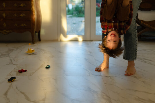 Happy child hanging upside down in mom's arms
