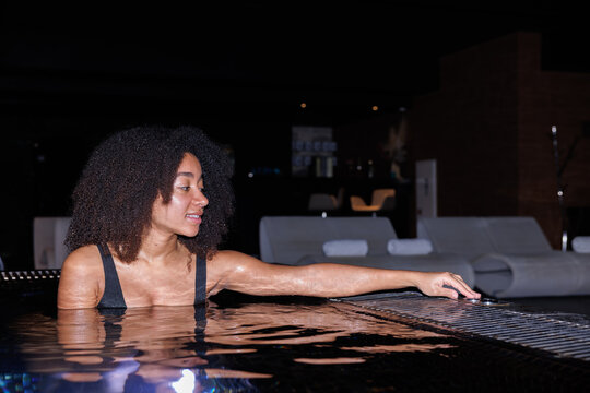 Beautiful black woman pushing button in jacuzzi pool at spa club