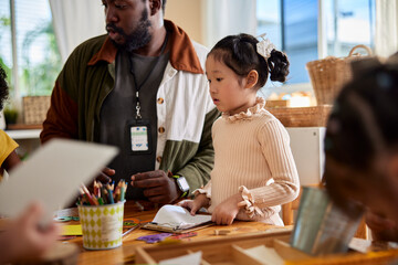 Cute girl with teacher at table in art class