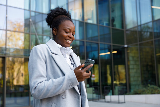 Graphic designer reading customer's opinion on phone standing outdoors