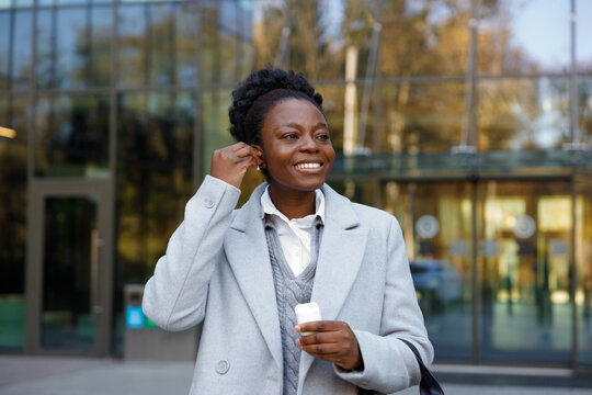 Smiling investor putting earphone in ear after leaving office 