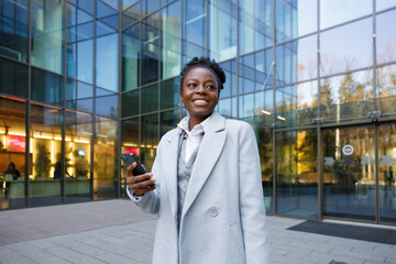Marketer standing with smartphone near commercial building entrance