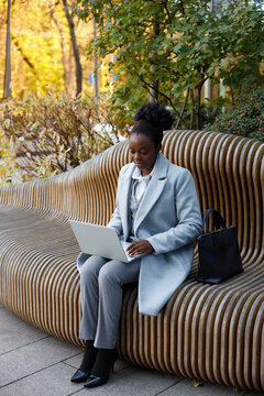 Female copywriter working remotely while sitting on bench in park