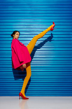 Model in bright tights posing with one leg extended high