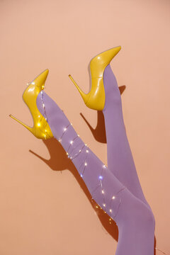 Stylish Legs in Yellow Heels Wrapped in Fairy Lights