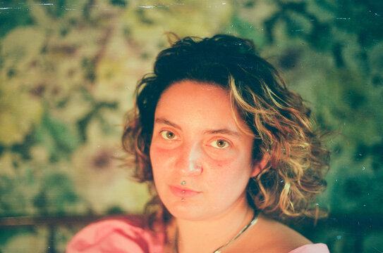 Young woman with piercings in bedroom, film portrait