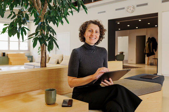 Formal businesswoman using digital tablet in modern office lounge